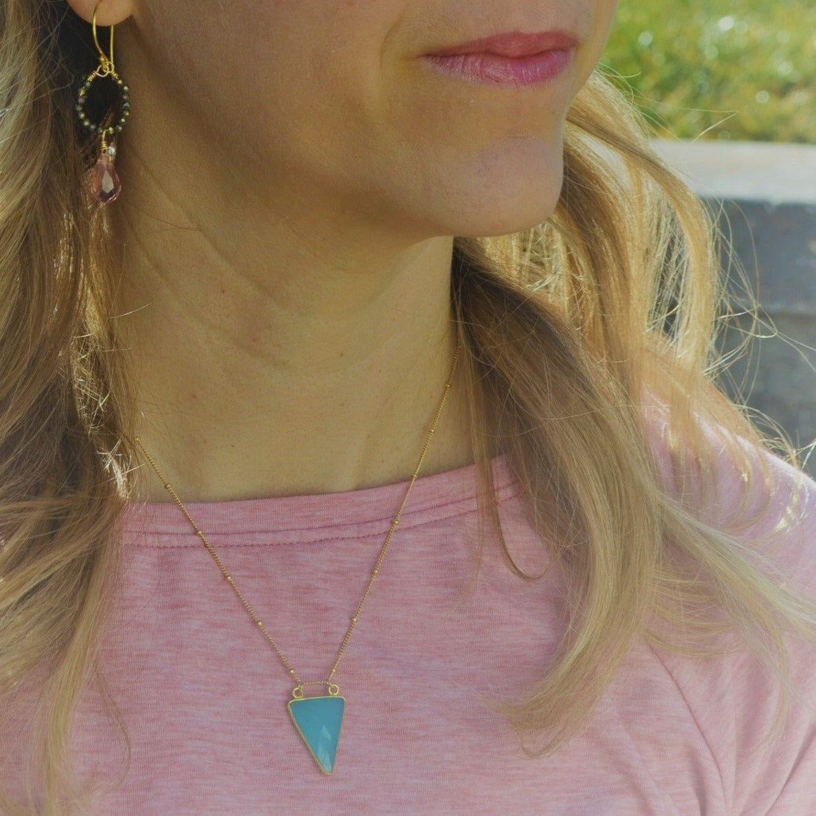 aqua chalcedony arrowhead pendant hanging on hold beaded necklace around neck of blonde girl with pink shirt and pink lipstick wearing hoop earings