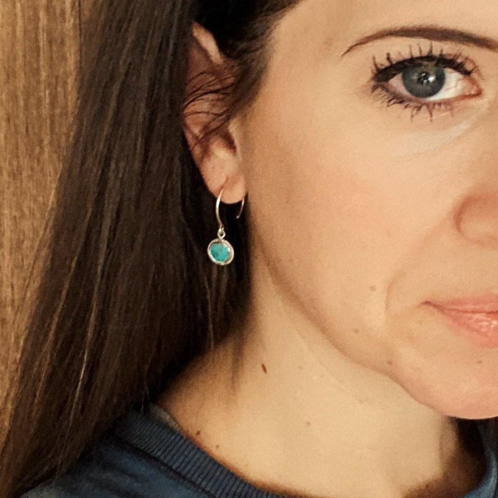 Arizona Turquoise Gem surrounded by sterling silver hanging on sterling silver metal hanging in ears of women with brunette hair