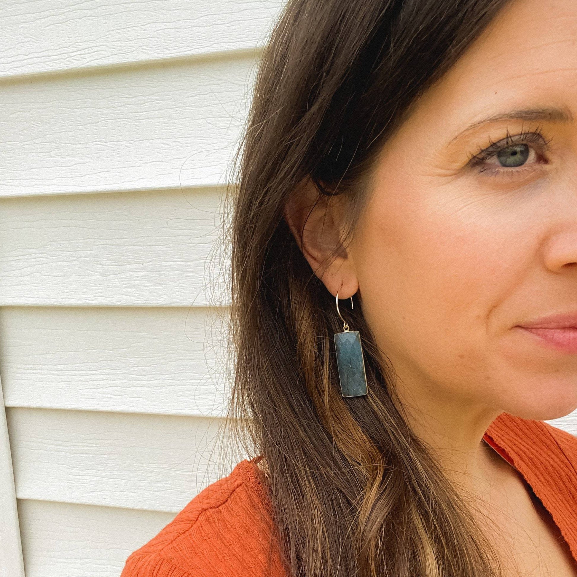 rectangle labrodorite earrings with gold metal hanging in ears of girl with brunette hair