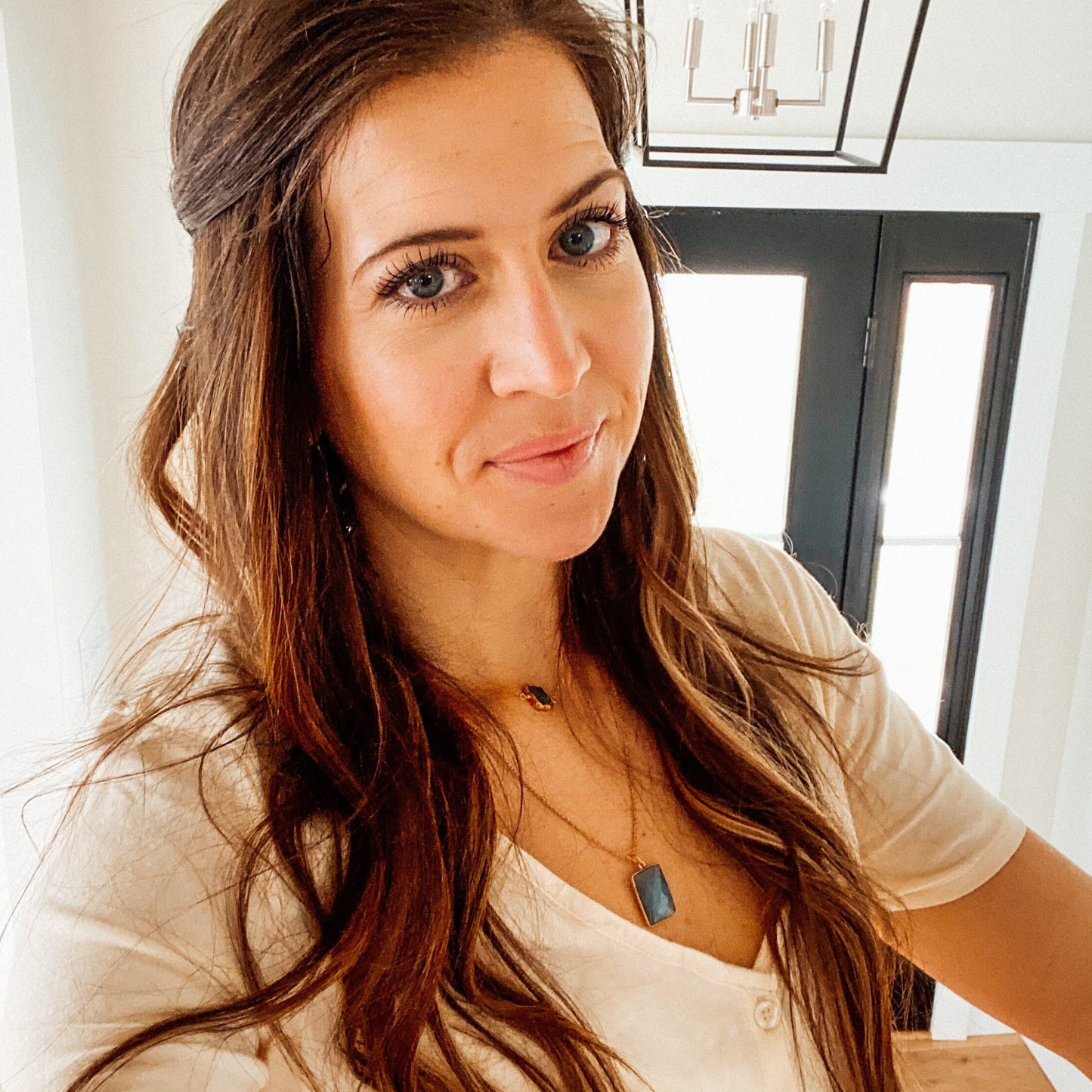 brunette girl wearing white shirt and blue eyes with beautiful blue square labrodorite bezzel pendent hanging on gold chain around her neck